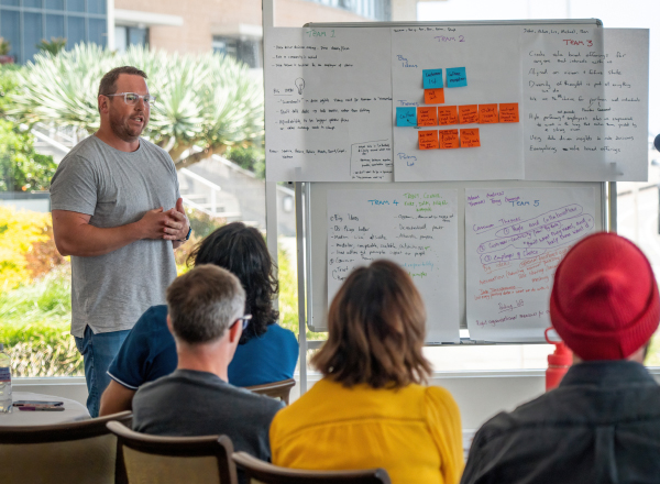 A male nib employee in front of a whiteboard, presenting at a workshop