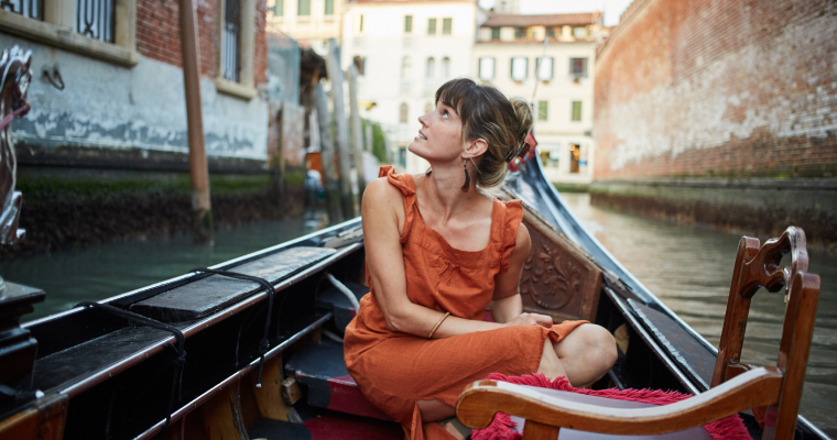 A woman on a gondola in a canal in Venice