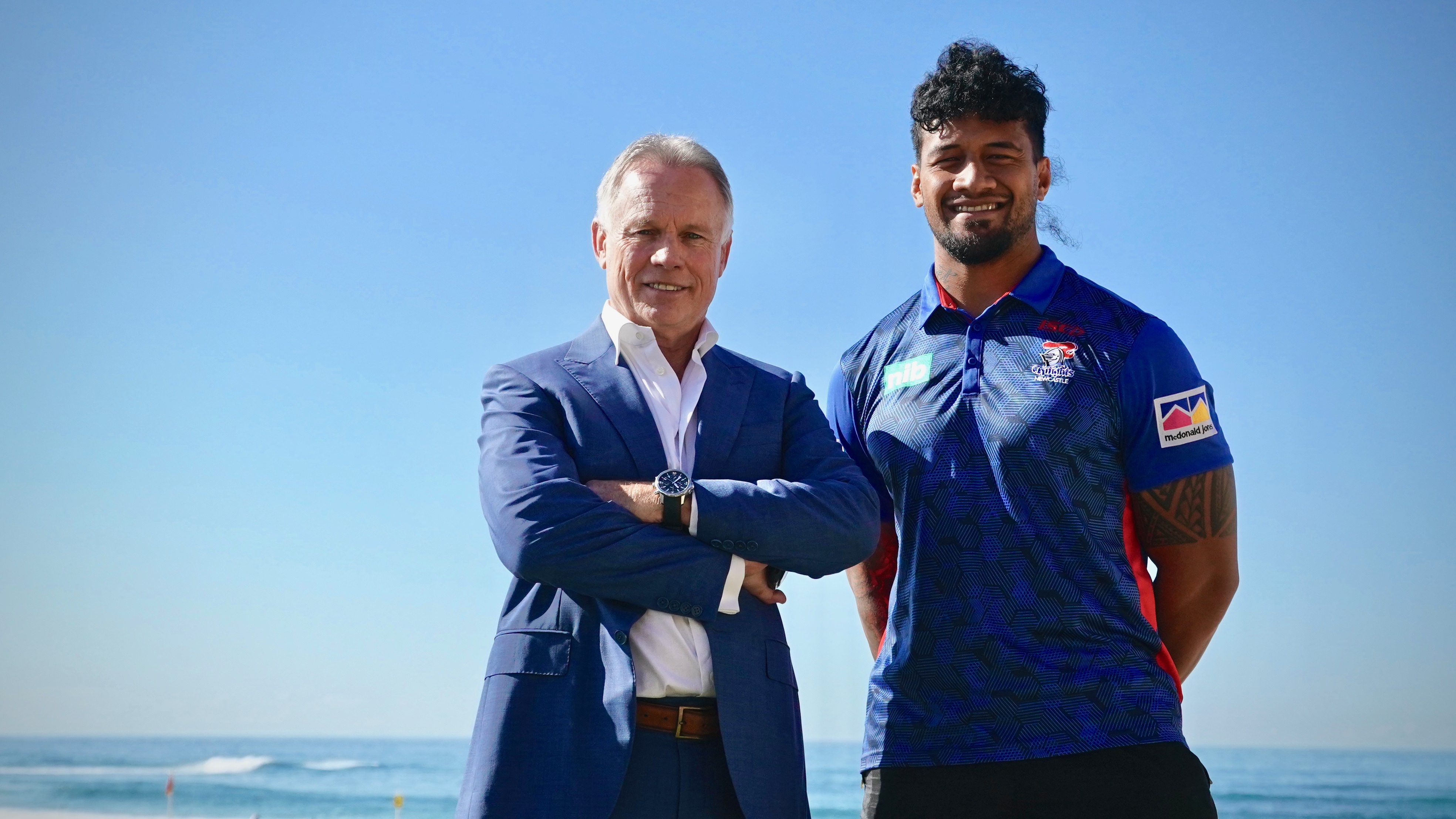 Mark Fitzgibbon with a Newcastle Knights player smiling together at the beach