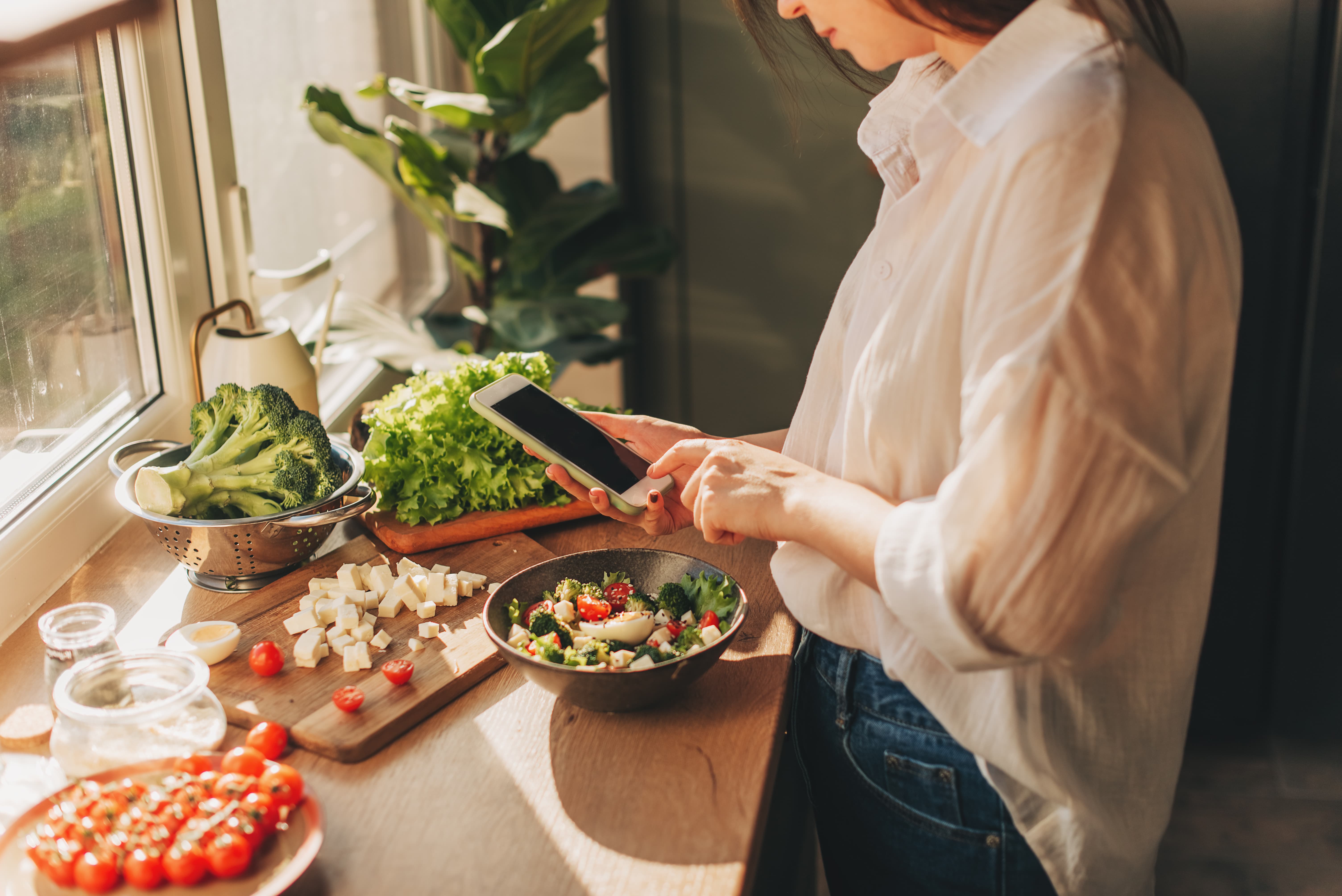 Person looking at a recipe on their phone while preparing food.