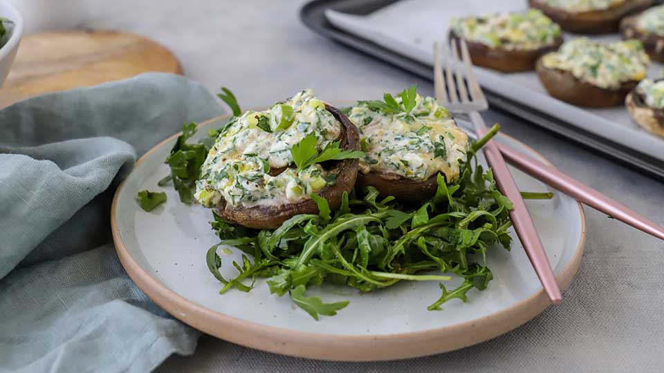 Lemon and herb stuffed mushrooms on a plate on a bed of rocket.