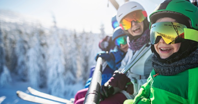 Children sitting on a ski lift smiling