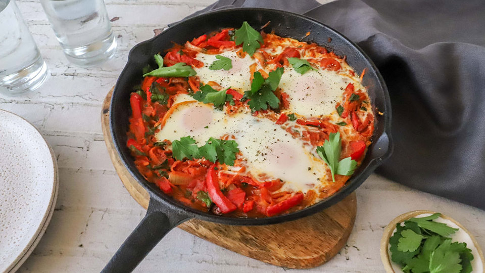 Shakshuka with sweet potato hash in cast iron pan.