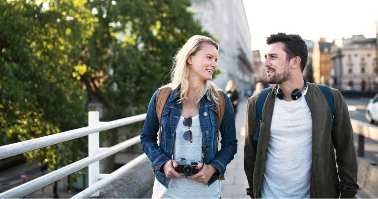 A man and a woman smiling to each other while walking across a bridge