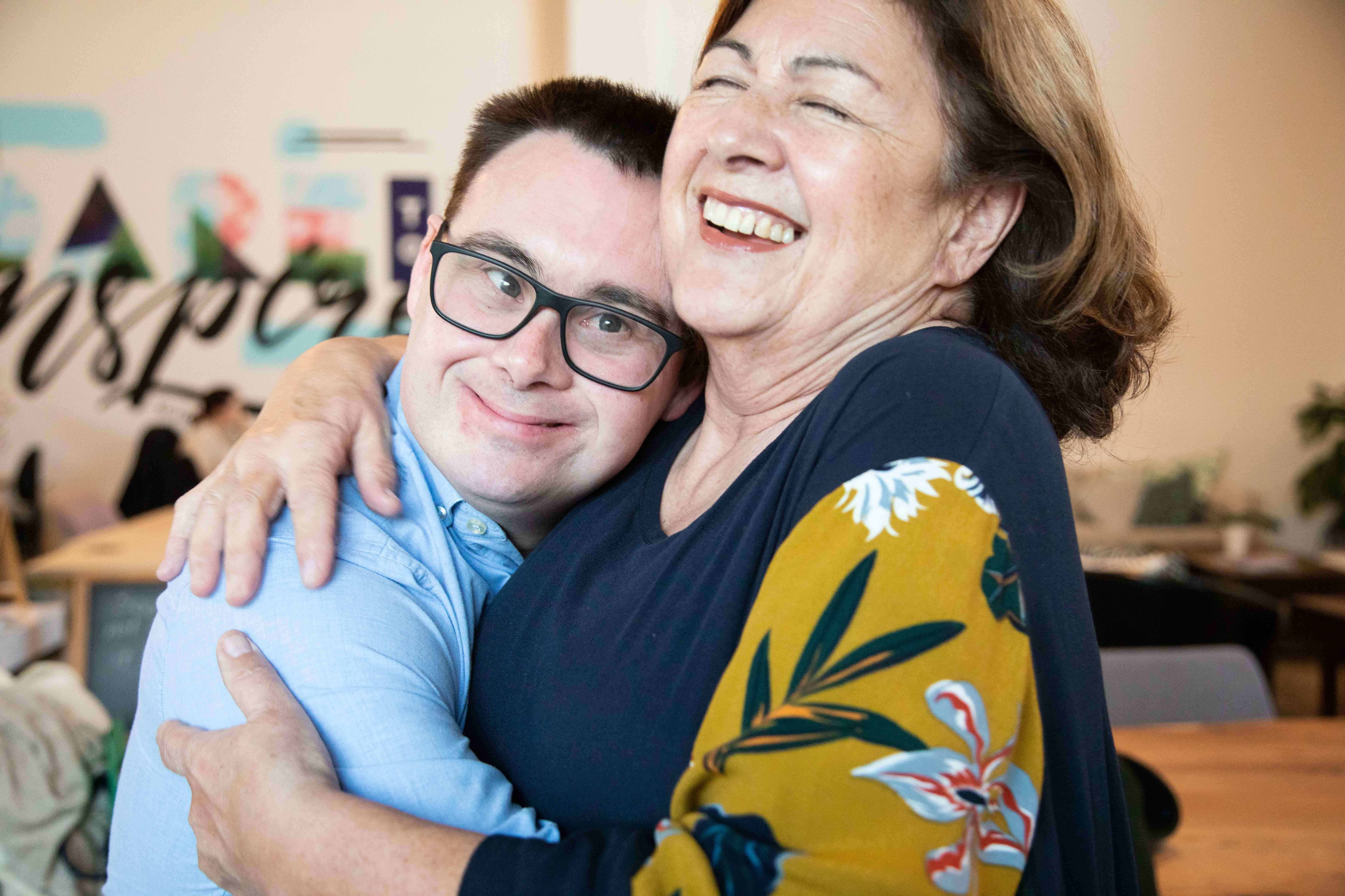 An adult man with down syndrome hugs his mum