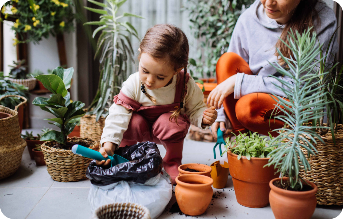 Cute Girl Planting Flowers With Mother At House Balcony