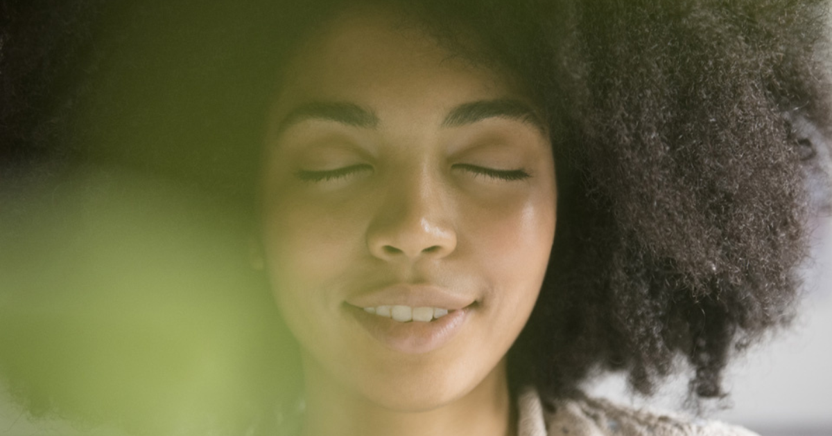 A close-up of a woman smiling while she closes her eyes.