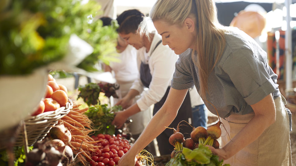 Woman picking vegetables at a green grocer.