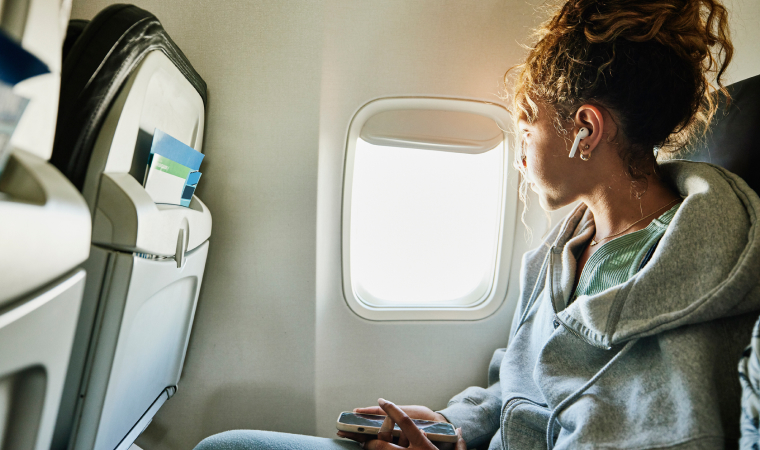 A woman sitting on a plane and looking out the window