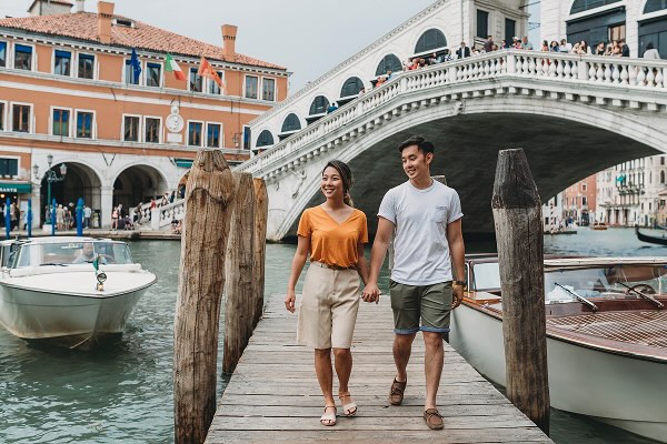 A couple walking hand in hand in front of the Ponte di Rialto