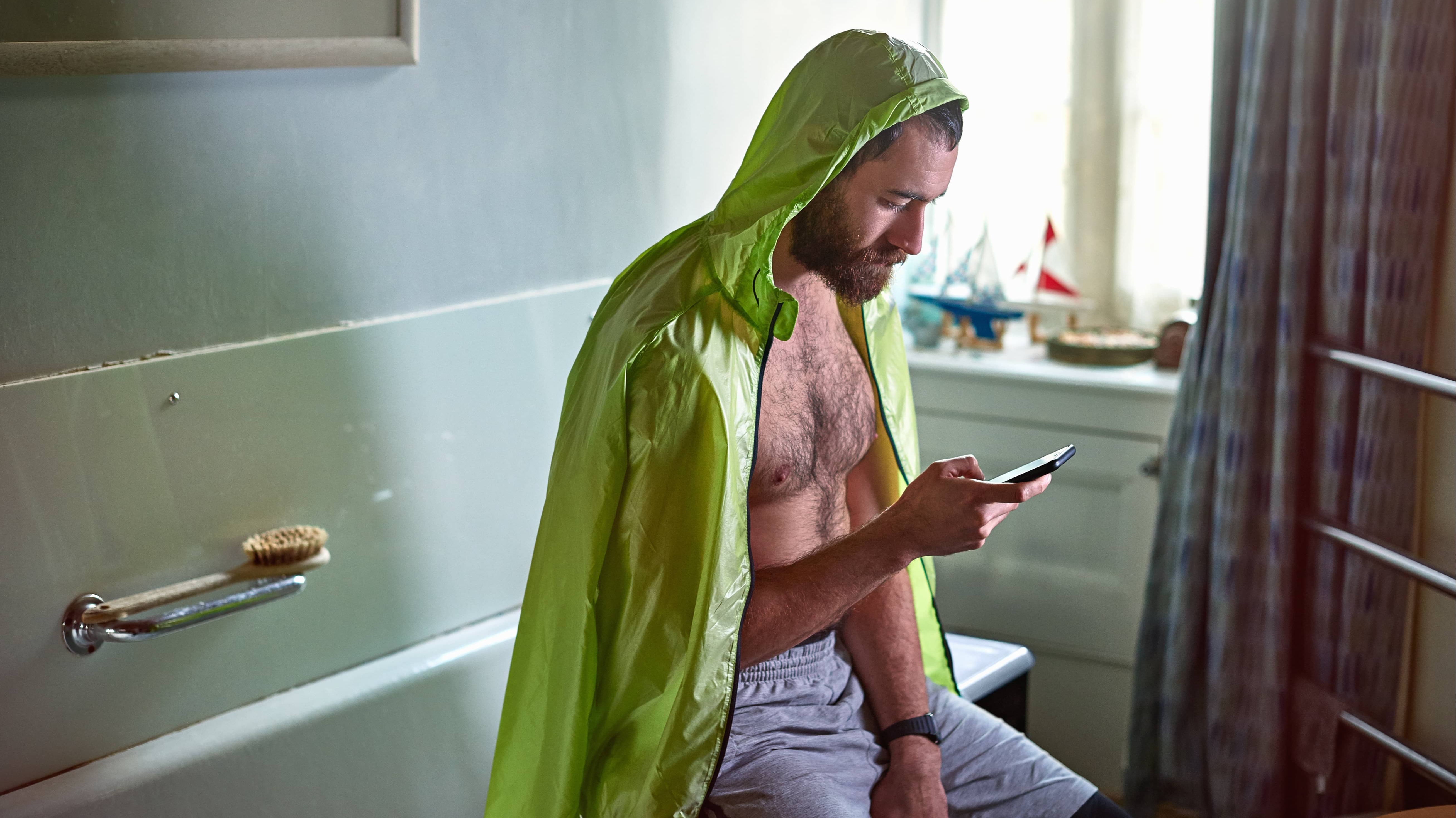 Person sitting on a bathtub, looking at their phone.