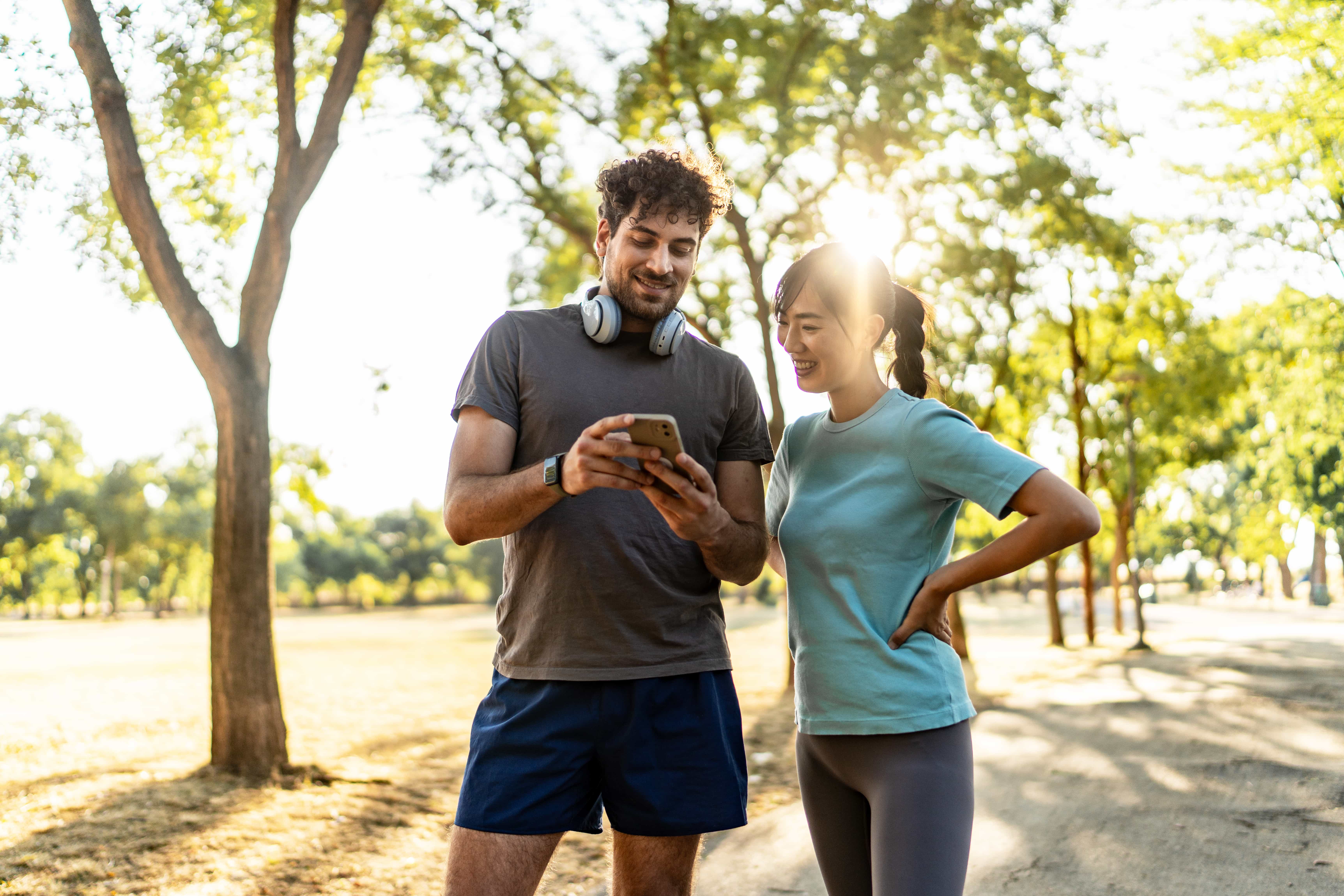 Couple standing and looking at a phone in a park.