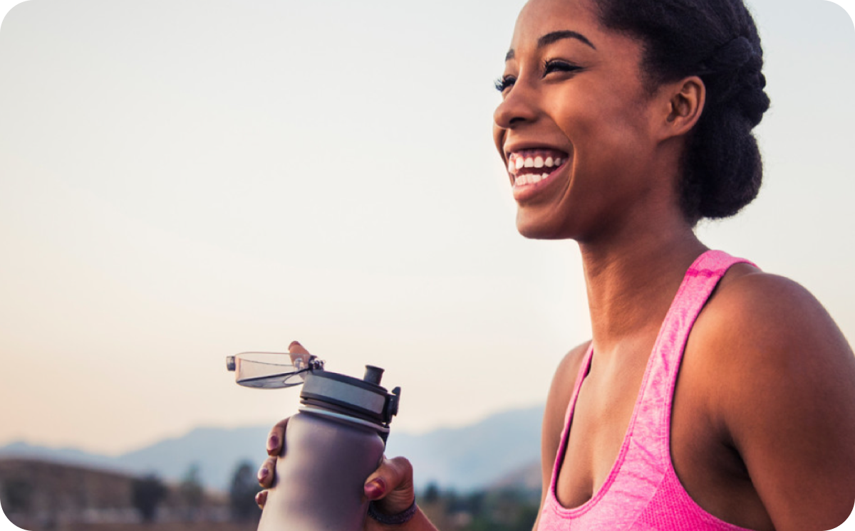 Woman out for a run holding a water bottle and smiling