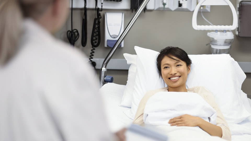 A young woman in a hospital smiles at her doctor