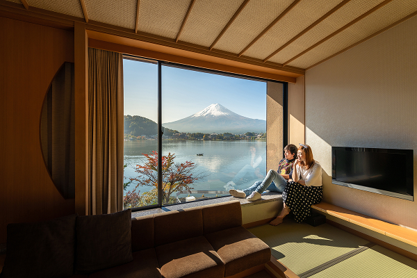 Two people sitting in a window of a house in Japan, with a view of Mt Fuji in the background