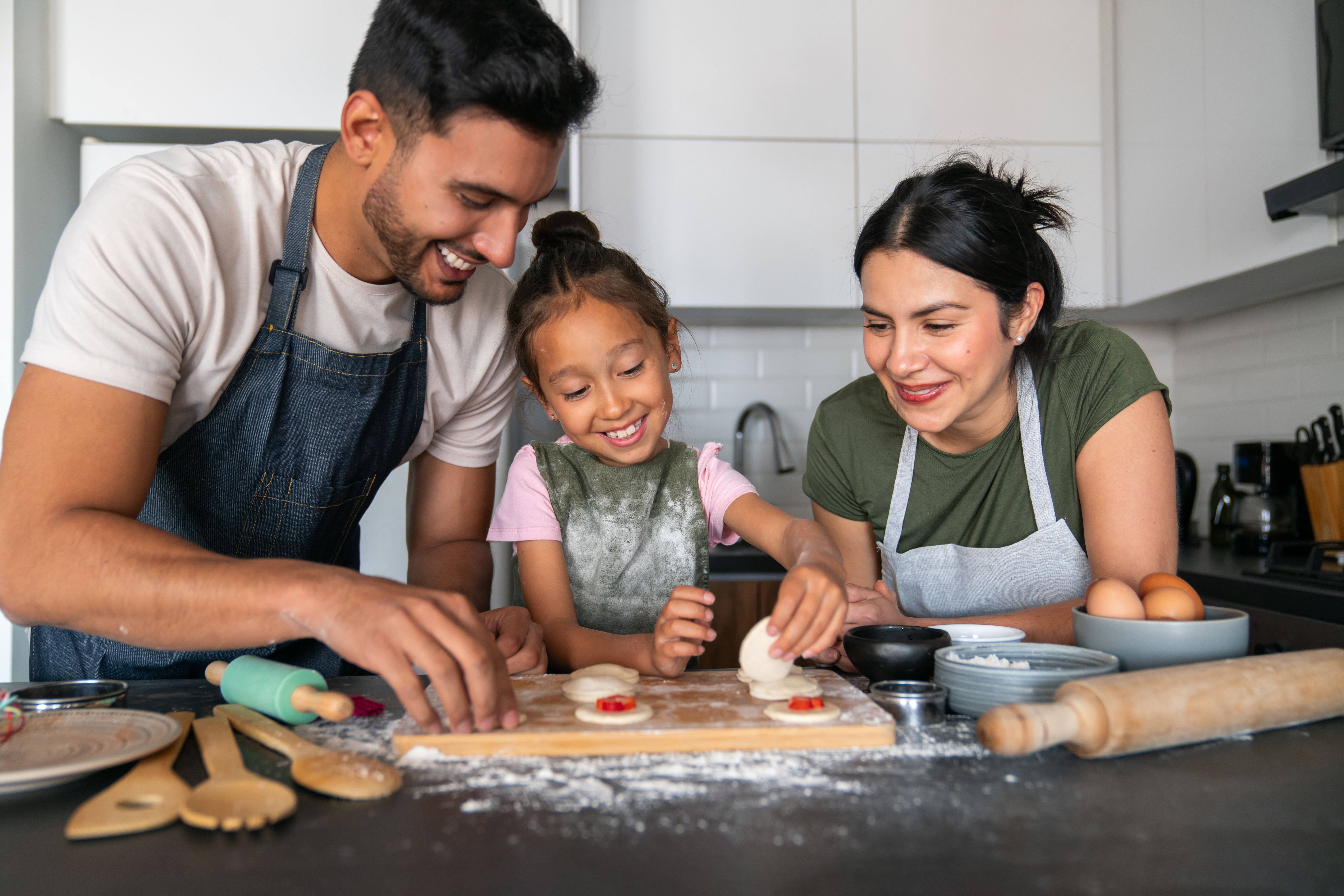 Mother and father cooking with daughter in kitchen.
