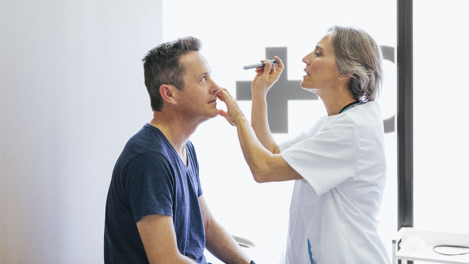 A female doctor checking a man's vitals in her office.