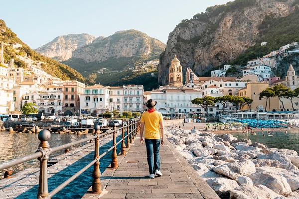 A man walking on a boardwalk in front of houses on the Amalfi COast