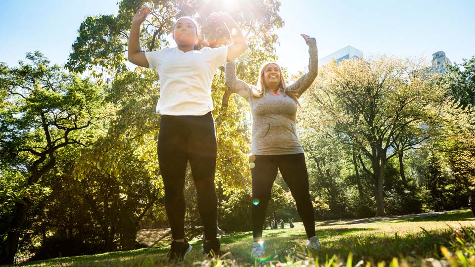 Two women exercise in a park.