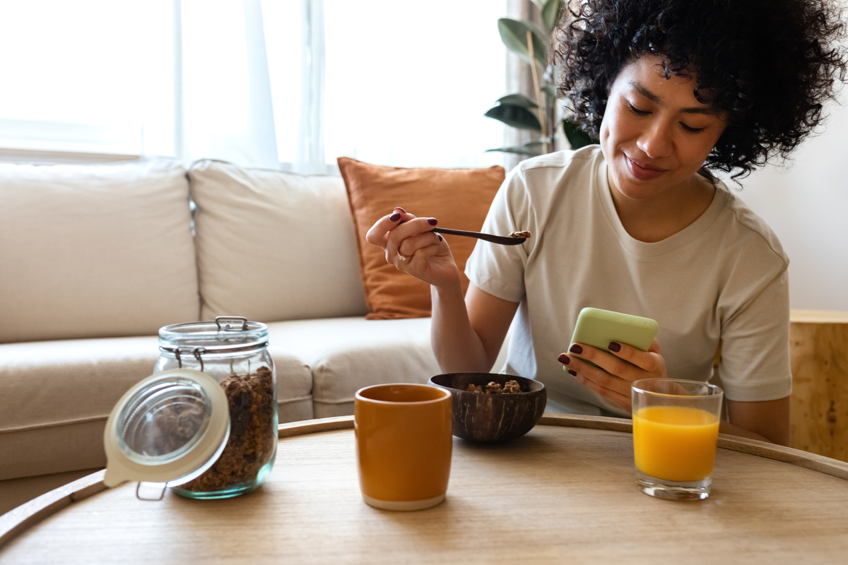 Woman looking at her phone while eating breakfast.