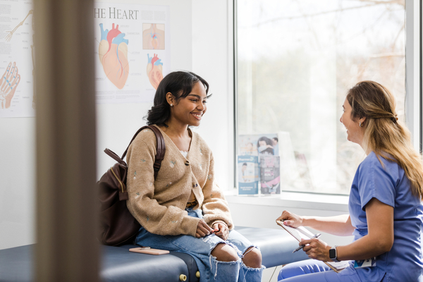 Young adult female patient smiles while listening to the nurse give an encouraging update regarding her health