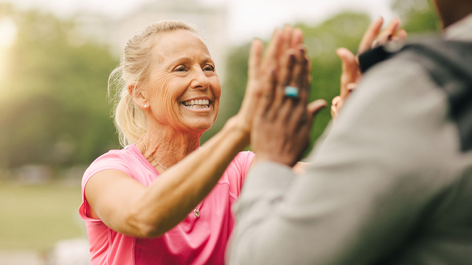 Senior woman high fiving a personal trainer.