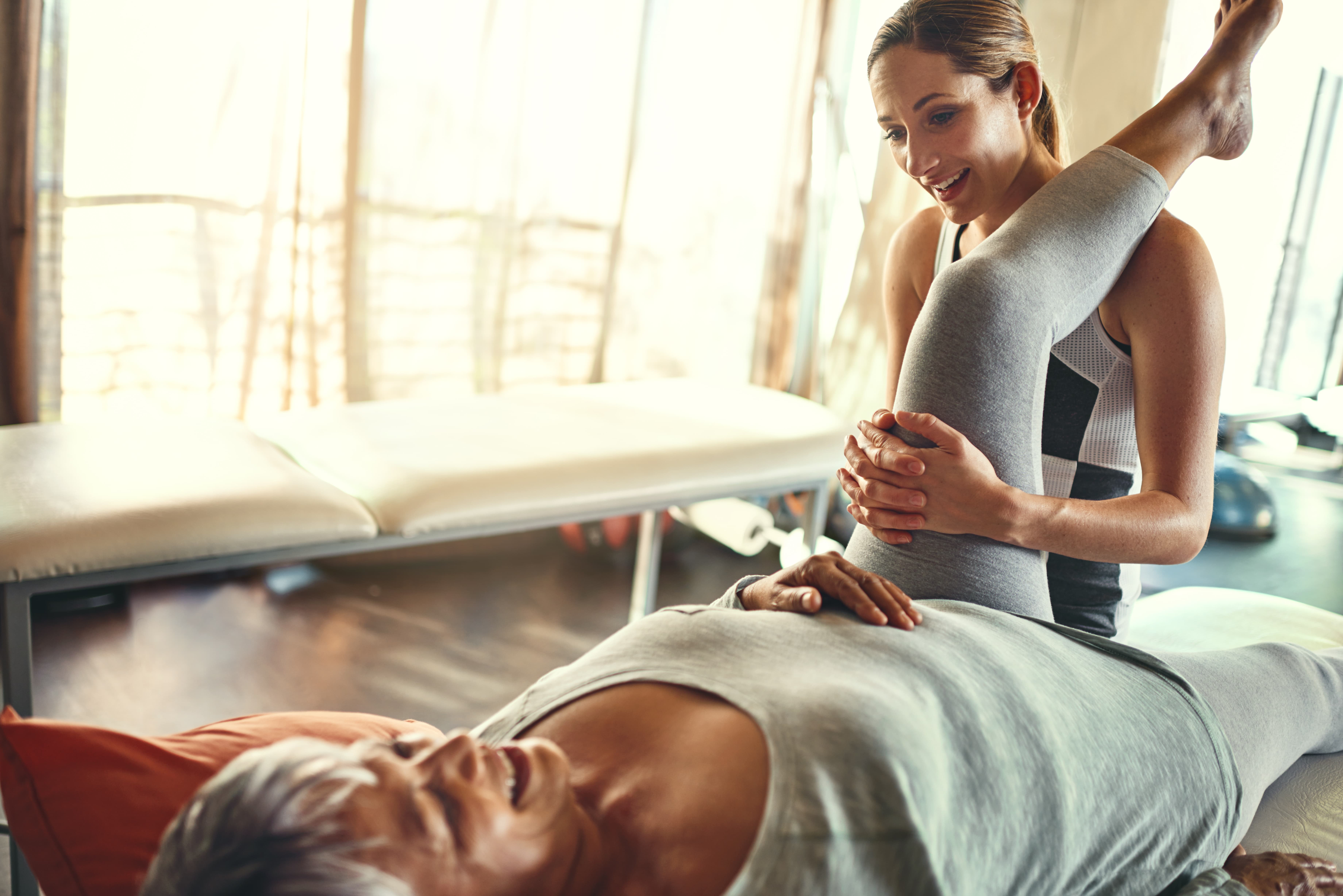 Physiotherapist stretching the leg of a woman.