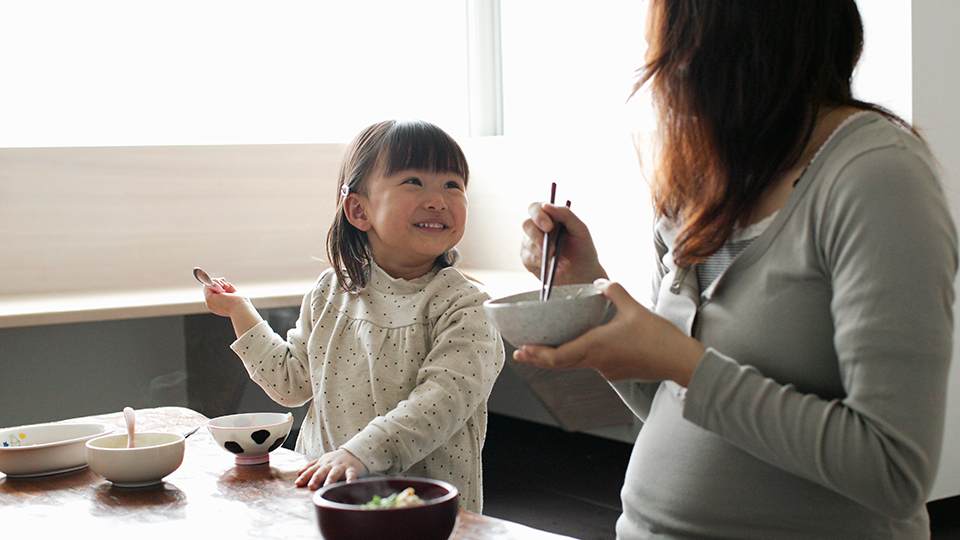 Pregnant mother and daughter enjoying a special moment together while eating.