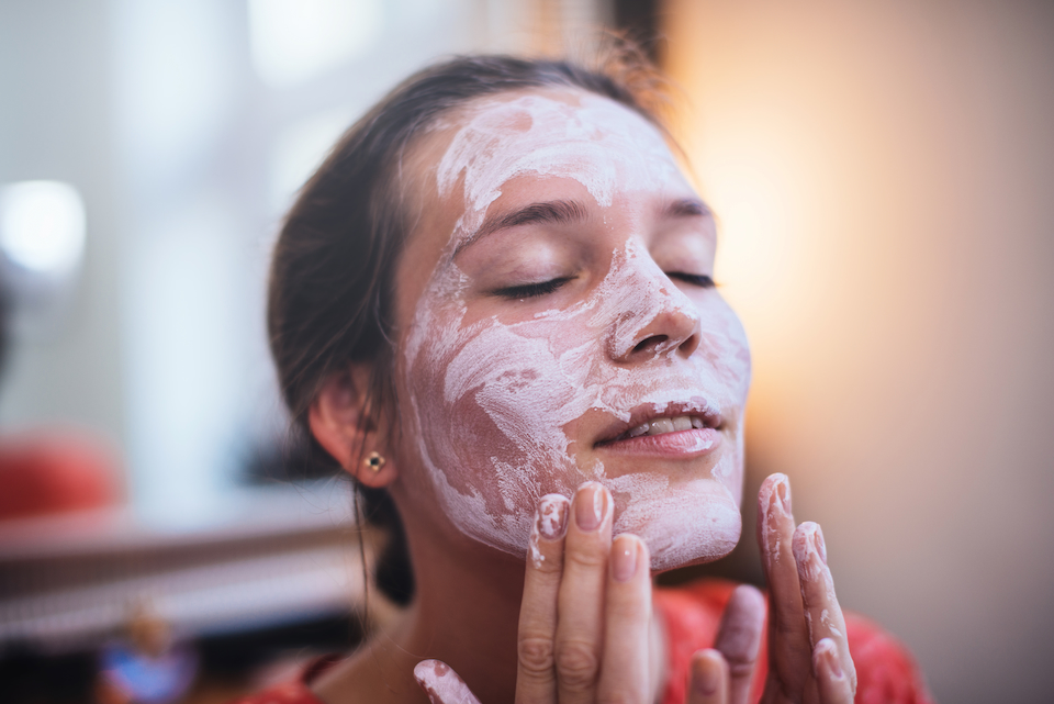 Woman using a facial mask with a relaxed look on her face.