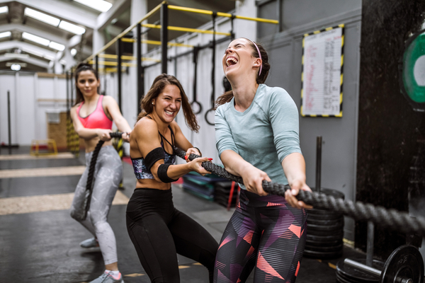 Three woman pulling gym rope and laughing.