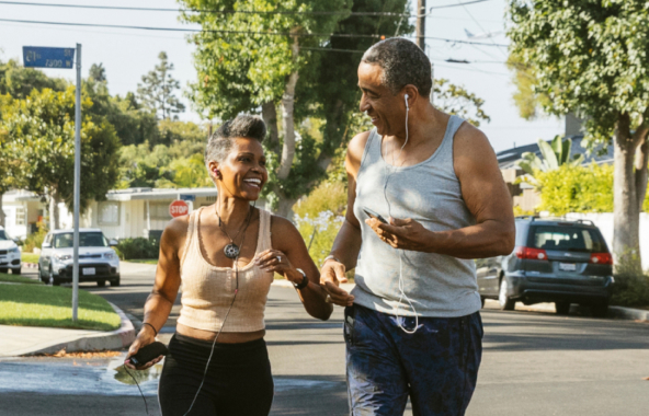 Man and woman smiling at each other as they run with headphones on.