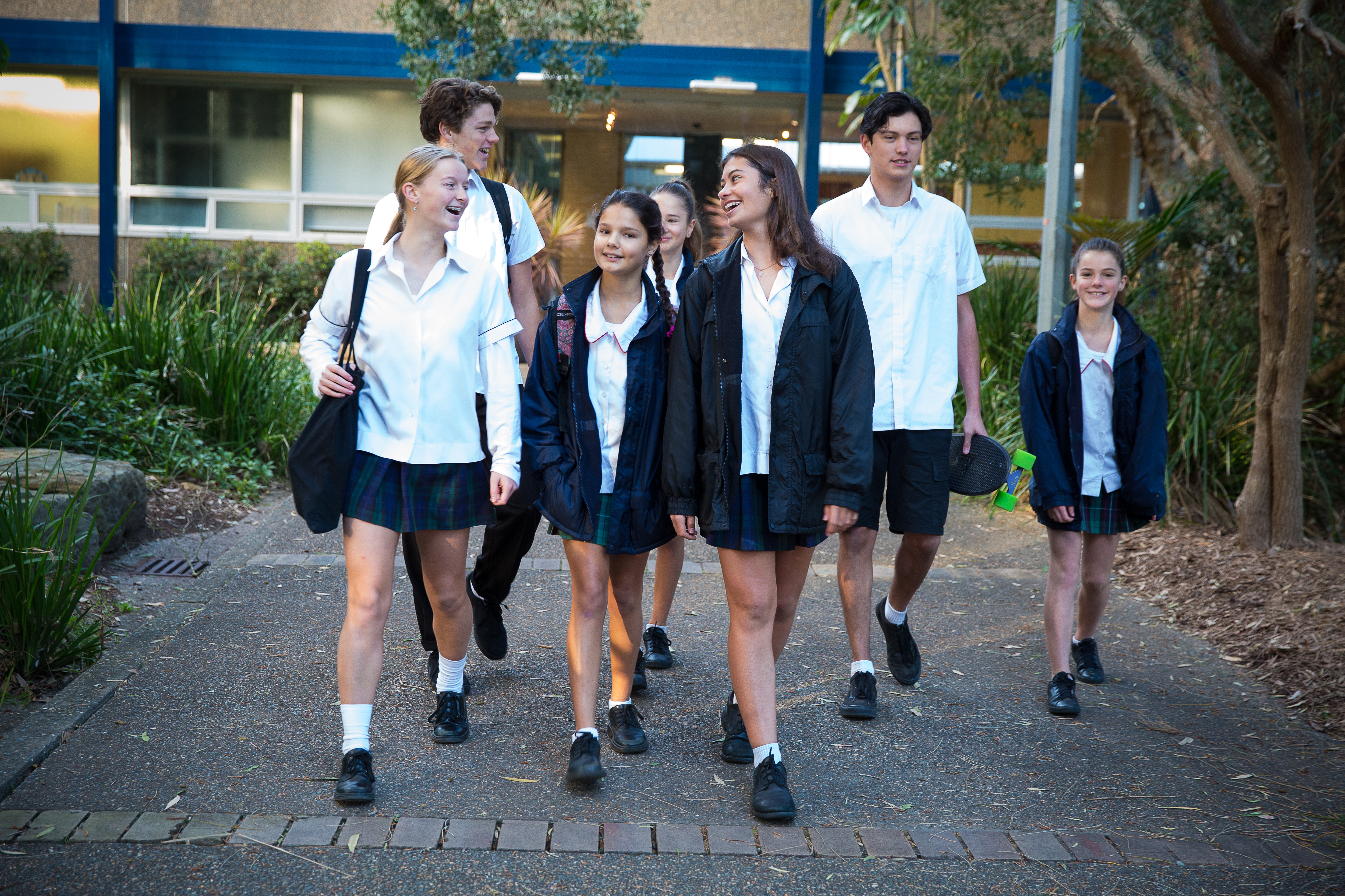 A group of teens talking and walking down the school path
