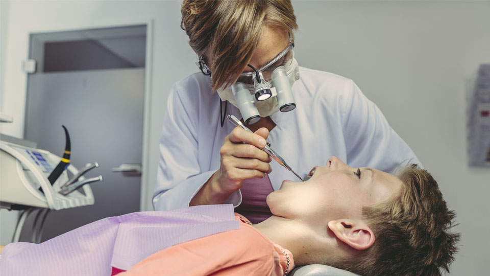 Dentist doing a dental check-up on teen boy.