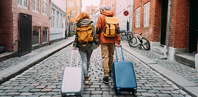 Two people pulling luggage on a road