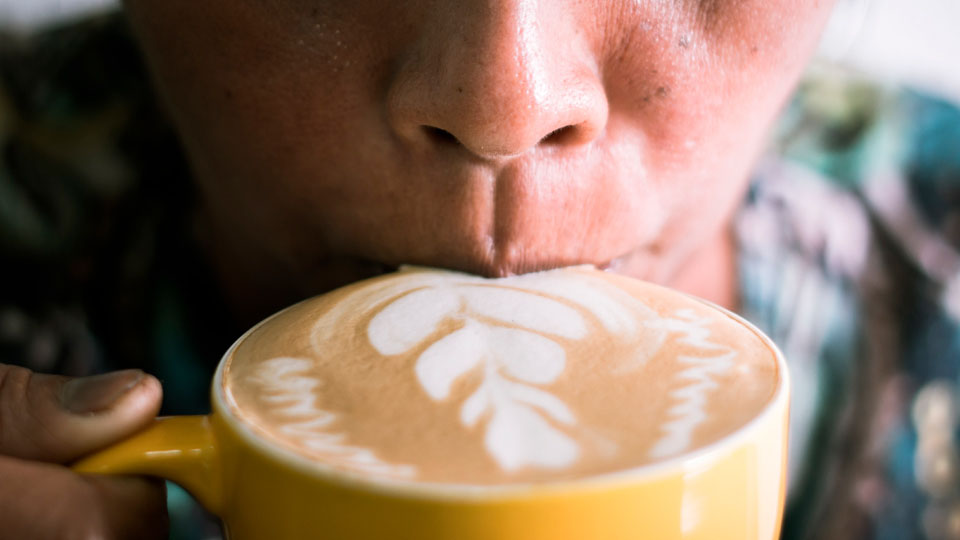 Close-up of someone taking a sip of a latte