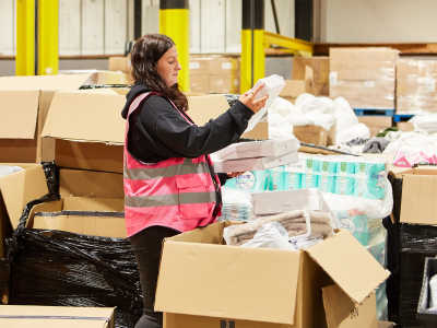 A woman unpacks boxes of bed linen at a the Brick by Brick multibank warehouse.