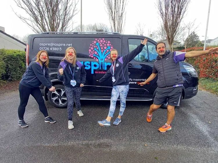 Four people wearing red noses standing in front of an Aspire van