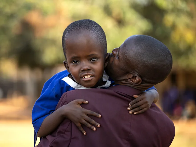A man holding a child who is looking at the camera