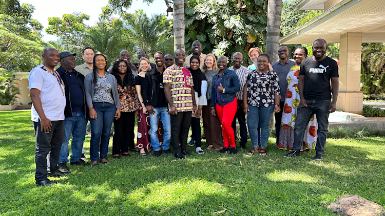 A group of people standing on the grass outside.