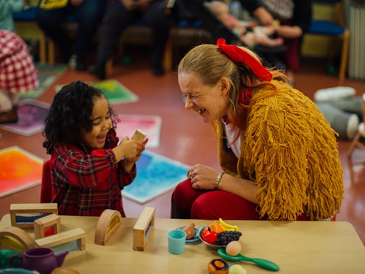 A young girl plays blocks with an older woman.