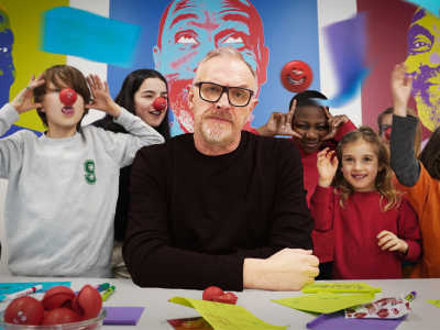 taskmaster greg davies surrounded by a group of school kids wearing red noses and teasing him