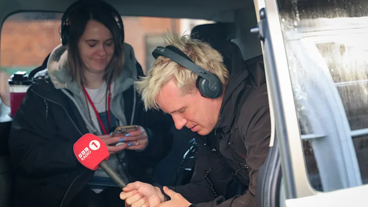 Jamie Laing sitting inside a van with a mic in hand