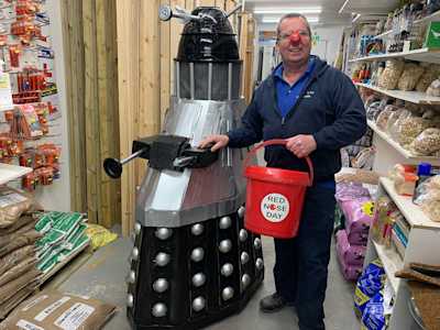 Person holding a fundraising basket standing next to a dalek