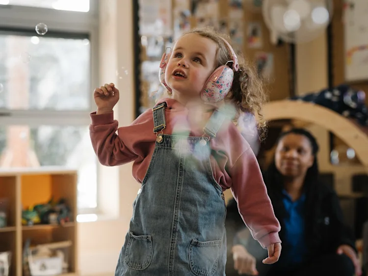 Little girl wearing headphones playing with bubbles