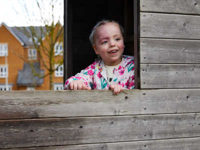 Nyla joyfully looks out the window of a cabin at the Dingley's Promise site.