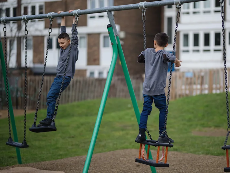 Two siblings playing on a swingset