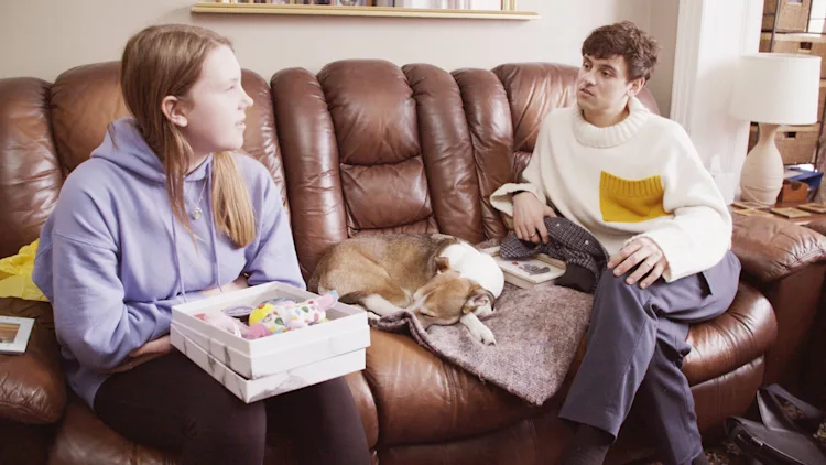 Matilda sits in her lounge with Tom Daley as her dog snoozes between them on the sofa