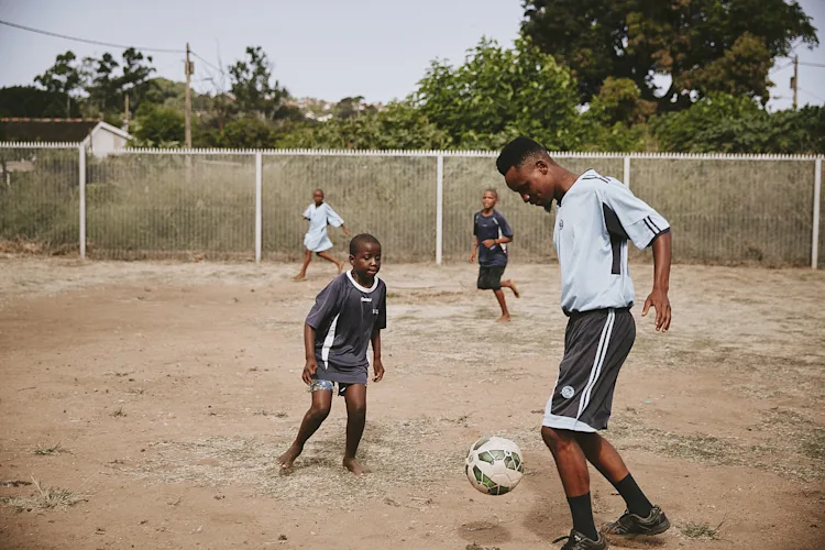 Lindo plays football with a child at iCare