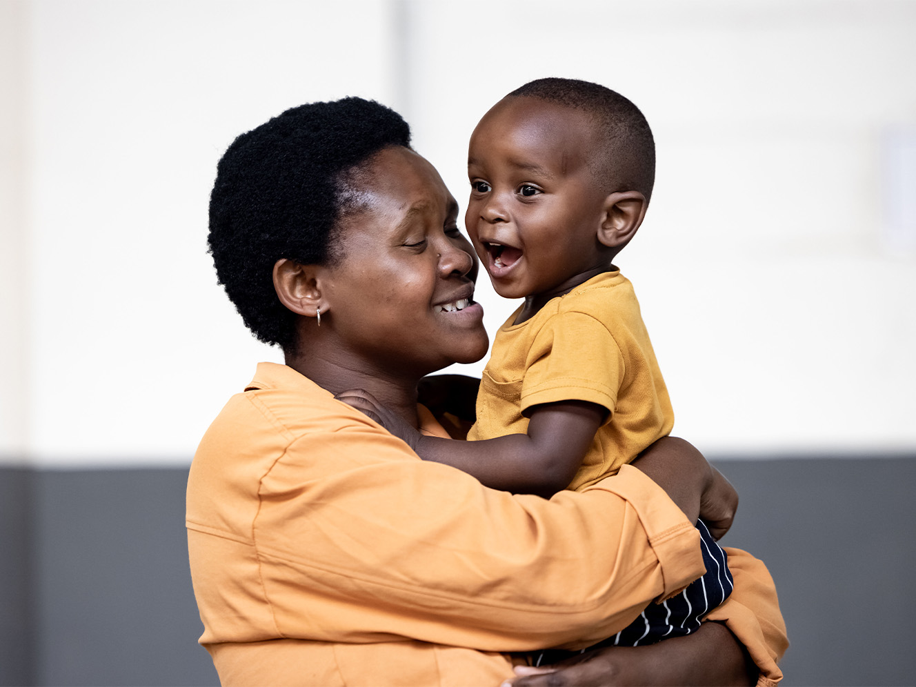 A woman carrying a toddler, both smiling