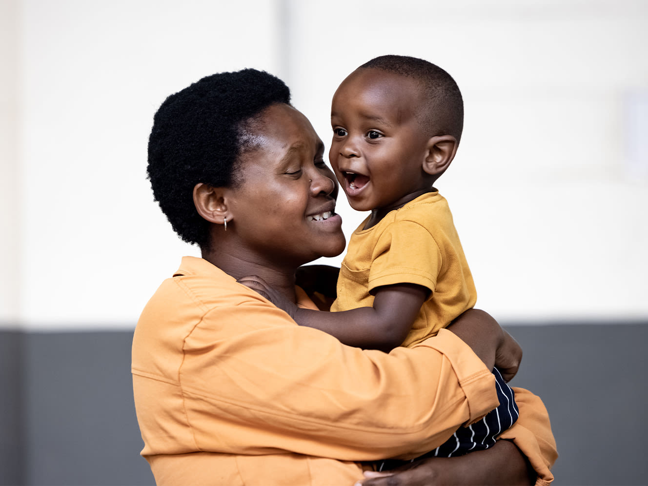 A woman carrying a toddler, both smiling